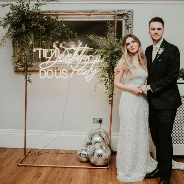 Bride and Groom standing in front of Neon Sign at Wedding