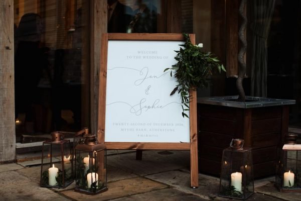 Wooden Welcome Sign at Wedding Entrance surrounded by Candles
