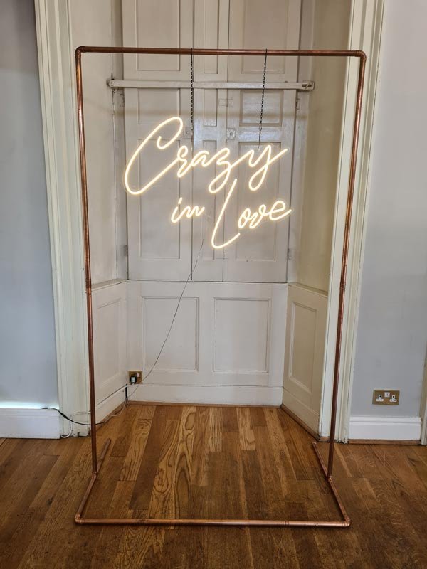 Crazy in Love Neon Sign hanging from Copper Arch at Wedding